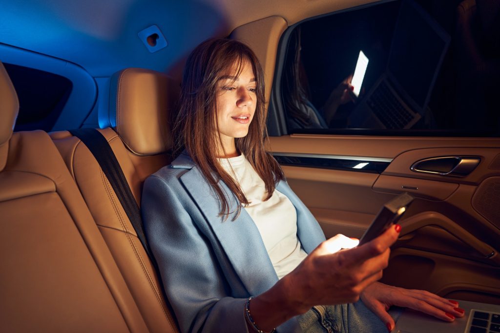 Smiling woman using mobile phone in car